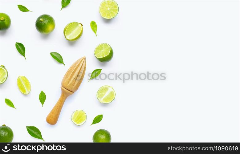 Fresh limes and leaves with wooden juicer on white background. Copy space