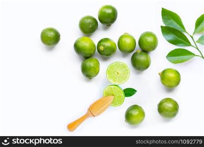 Fresh limes and leaves with wooden juicer on white background. Copy space