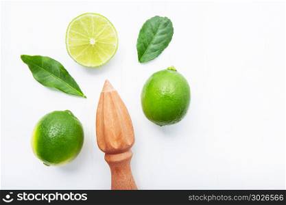 Fresh limes and wooden juicer on white background. Top view with copy space. Fresh limes and wooden juicer on white background. Top view with