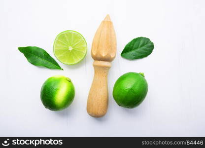 Fresh limes and wooden juicer on white background. Top view with copy space