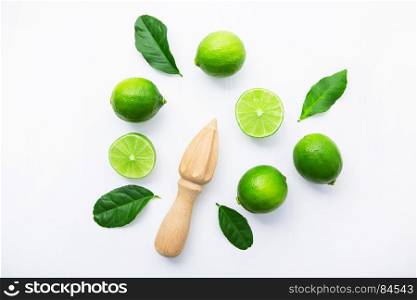 Fresh limes and wooden juicer on white background. Top view with copy space