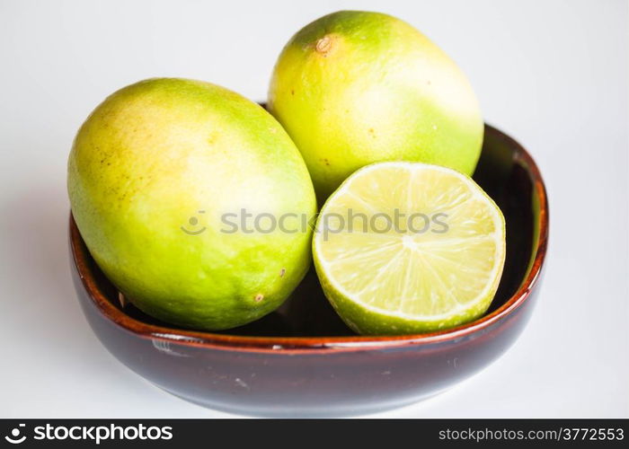 Fresh limes whole and slice in ceramic bowl