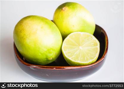 Fresh limes whole and slice in ceramic bowl
