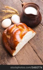 Fresh loaf of challah with milk and eggs on the table