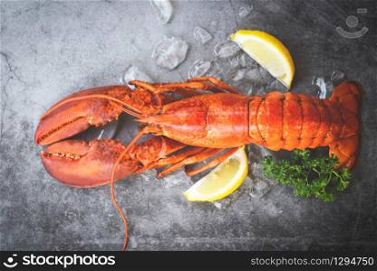 Fresh lobster food on a black plate background / red lobster dinner seafood with herb spices lemon served table and ice in the restaurant gourmet food healthy boiled lobster cooked , top view
