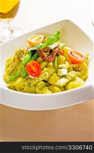 fresh lumaconi pasta and pesto sauce with vegetables and sundried tomatoes,tipycal italian food