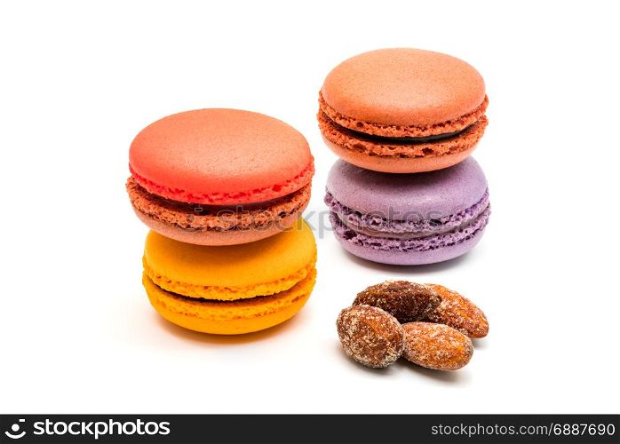 Fresh macarons and almonds on white background