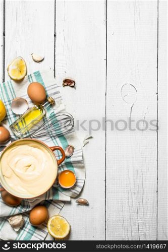 Fresh mayonnaise with the ingredients. On a white wooden background.. Fresh mayonnaise with the ingredients.
