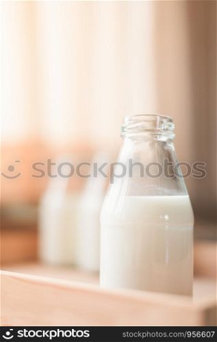 Fresh milk bottles without cap on wooden box near the window. A healthy drink concept. Copy space wallpaper.