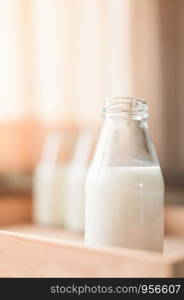 Fresh milk bottles without cap on wooden box near the window. A healthy drink concept. Copy space wallpaper.
