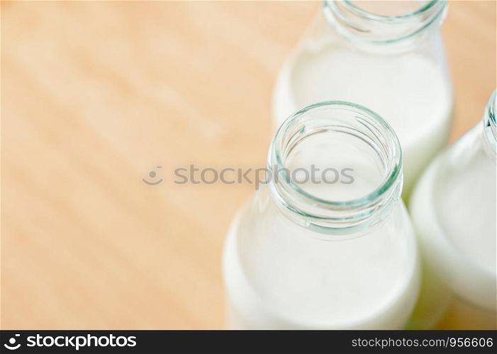 Fresh milk bottles without cap on wooden table near the window. A healthy drink concept. Copy space wallpaper.