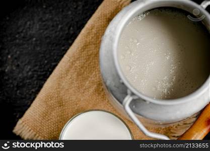 Fresh milk in a can on the table. On a black background. High quality photo. Fresh milk in a can on the table.