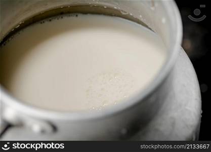 Fresh milk in a can on the table. On a black background. High quality photo. Fresh milk in a can on the table.