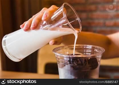 Fresh milk pouring into glass with frozen chocolate