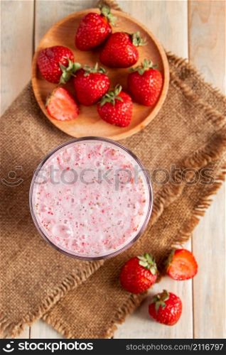 Fresh milkshake with strawberries. Summer drink with berries in a glass on a wooden background. Vertical photo. Fresh milkshake with strawberries. Summer drink with berries in a glass on wooden background.