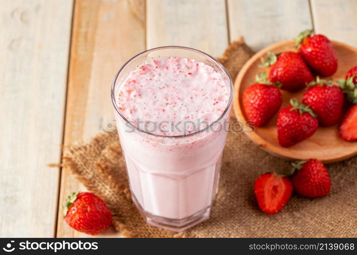 Fresh milkshake with strawberries. Summer drink with berries in a glass on a wooden background.. Fresh milkshake with strawberries. Summer drink with berries in a glass on wooden background.