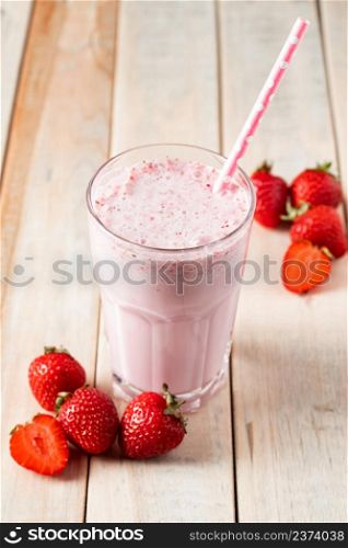 Fresh milkshake with strawberries. Summer drink with berries in a glass on a wooden background. Vertical photo. Fresh milkshake with strawberries. Summer drink with berries in a glass on wooden background.