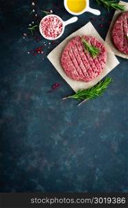 Fresh minced beef meat burgers with spices on dark background. Raw ground beef meat. Flat lay. Top view