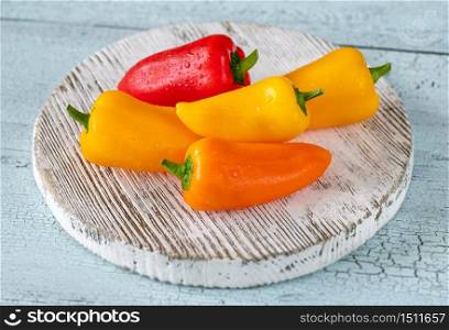 Fresh mini sweet peppers on wooden board