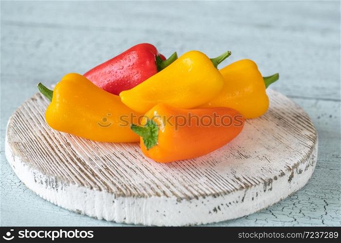 Fresh mini sweet peppers on wooden board