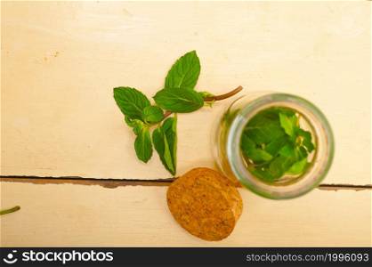 fresh mint leaves on a glass jarover a rustic white wood table