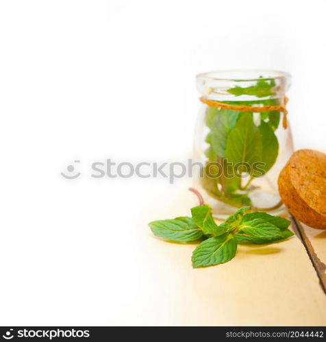 fresh mint leaves on a glass jarover a rustic white wood table