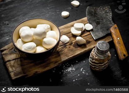 Fresh mozzarella with a hatchet for cutting. On a black wooden background.. Fresh mozzarella with a hatchet for cutting.