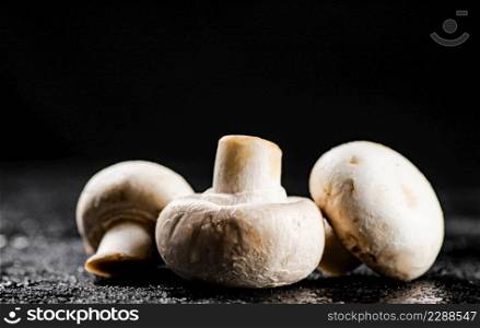 Fresh mushrooms champignons on the table. On a black background. High quality photo. Fresh mushrooms champignons on the table.