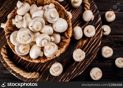 Fresh mushrooms in a basket on a wooden tray. On a wooden background. High quality photo. Fresh mushrooms in a basket on a wooden tray.
