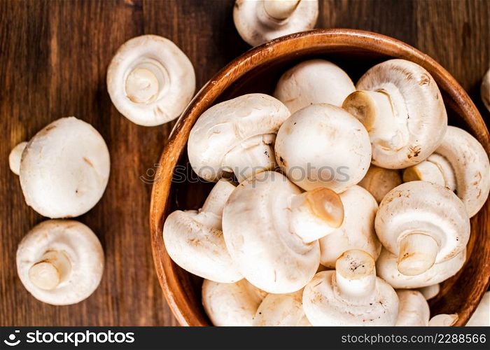 Fresh mushrooms in a wooden bowl. On a wooden background. High quality photo. Fresh mushrooms in a wooden bowl.