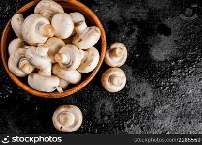 Fresh mushrooms in a wooden plate. On a black background. High quality photo. Fresh mushrooms in a wooden plate.