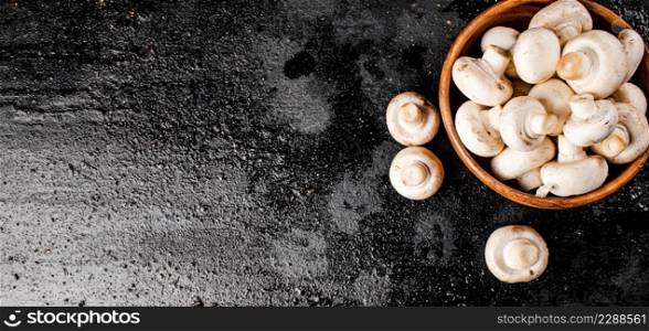 Fresh mushrooms in a wooden plate. On a black background. High quality photo. Fresh mushrooms in a wooden plate.