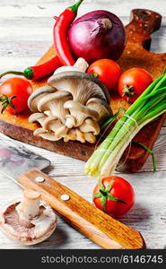 Fresh mushrooms,tomatoes,peppers and onions on a light wooden background