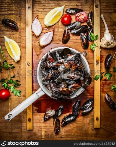 Fresh mussels in old colander with ingredients for tasty cooking on wooden background, top view. Seafood concept