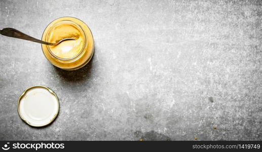 Fresh mustard in a jar with a spoon. On the stone table.. Fresh mustard in a jar