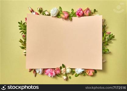Fresh natural organic flower frame with paper congratulation card on a light olive background with copy space. Valentine&rsquo;s greeting card.. Paper congratulation card with flowers frame.