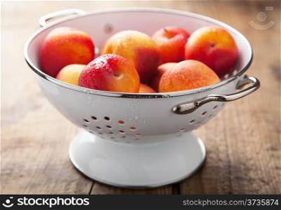 fresh nectarines and plums in colander