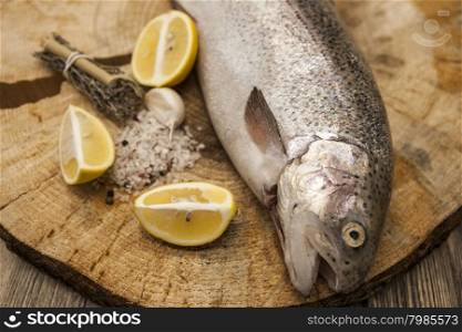 Fresh Norwegian rainbow trout with lemon and onions on a wooden background. Fresh Norwegian rainbow trout with lemon and onions on a wooden background.