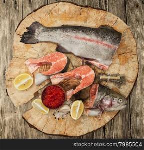 Fresh Norwegian rainbow trout with lemon red caviar, and onions on a wooden background.