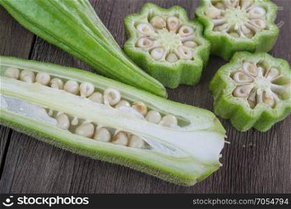 fresh okra vegetable also known as lady&rsquo;s fingers on old wooden background