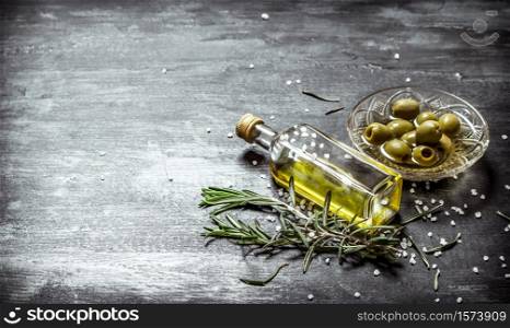 Fresh olives and the oil in the bottle with the rosemary. On black rustic background.. Fresh olives and the oil