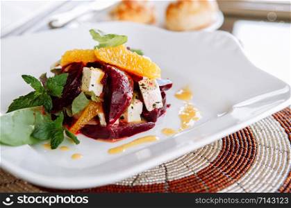 Fresh orange and beetroot salad with Arugula and Feta cheese and citrus juice dressing in with plate close up view