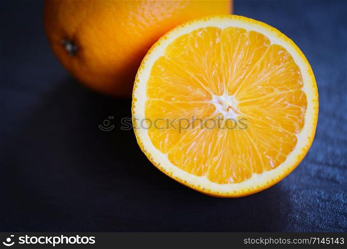 Fresh orange fruit slice half on dark background