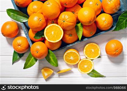 Fresh orange fruits with leaves on wooden table