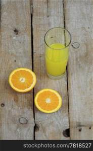 Fresh orange juice and two halves of a fruit on wooden table