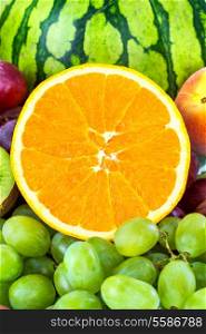 Fresh Orange on a background of different fruits and grapes