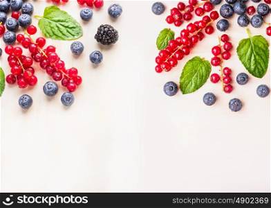 Fresh organic berries with mint leaves and water drops on white wooden background, top view, place for text