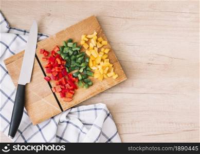 fresh organic chopped red yellow green bell peppers chopping board with knife wooden desk