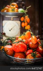 Fresh organic farm tomatoes over dark wooden background and vintage scales. Still life scene