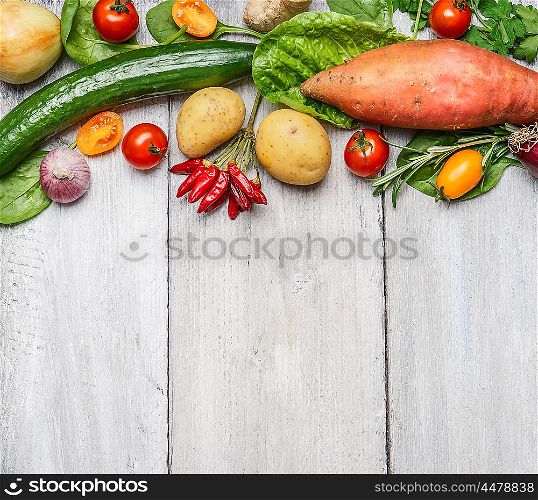 Fresh organic farm vegetables and ingredients for healthy cooking on white wooden background, border, top view. Vegetarian or diet food concept